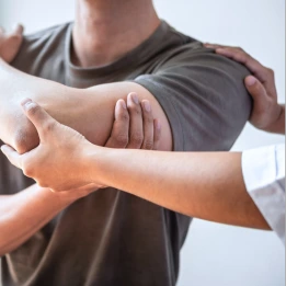 A healthcare professional provides pain management and care at home by gently supporting a patient's arm during a physical therapy session. The image highlights at-home pain relief and rehabilitation support for improved mobility.